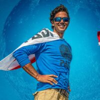 man draped in padi flag standing in a superhero pose