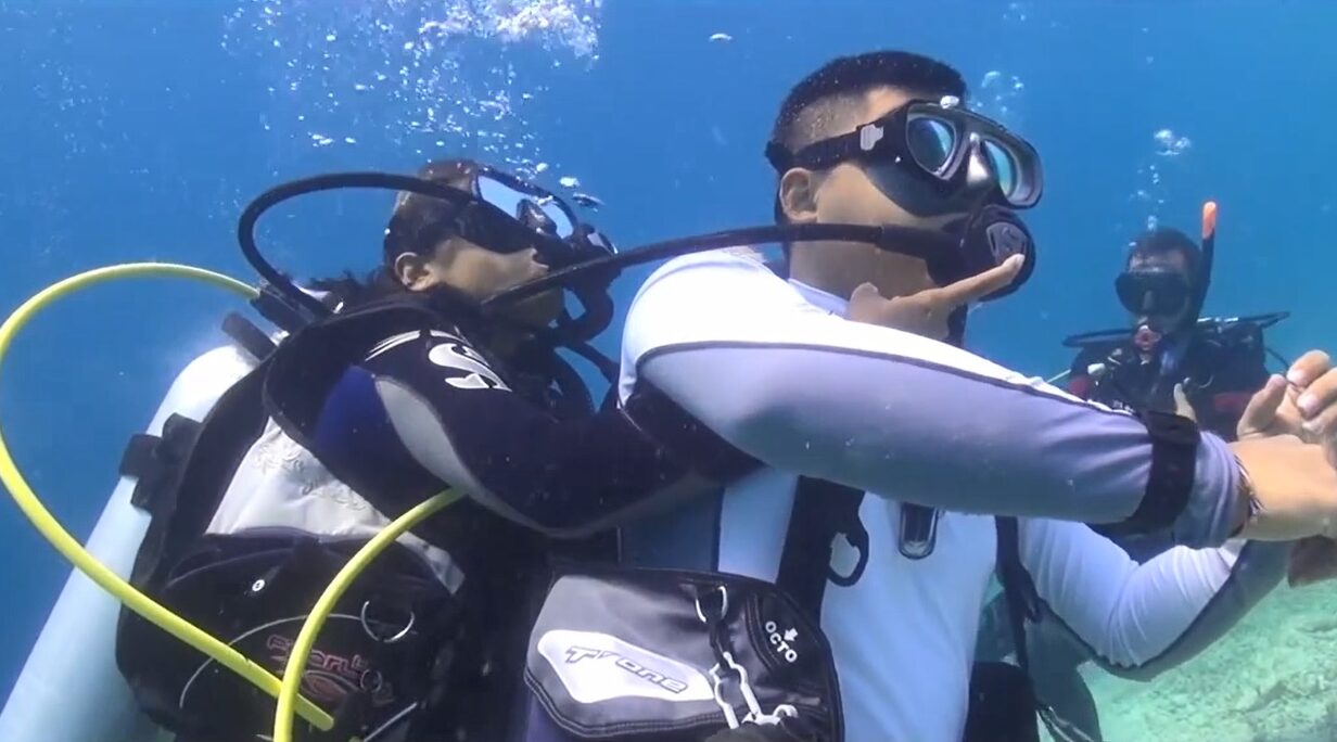 two divers practice surfacing an unresponsive diver underwater