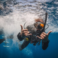 a scuba diver gives the double hang loose symbol underwater