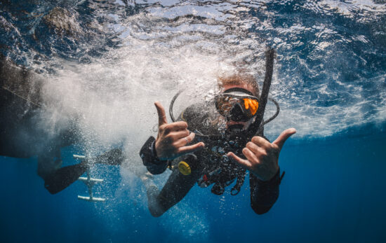 a scuba diver gives the double hang loose symbol underwater