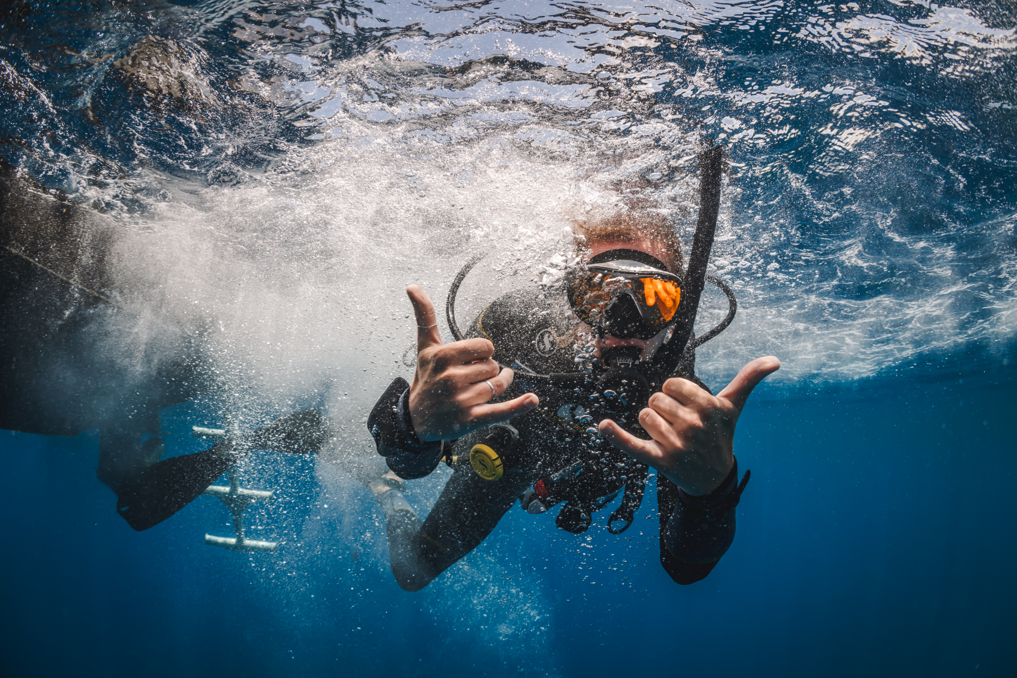 Um mergulhador dá o símbolo de "hang loose" duplo embaixo d'água