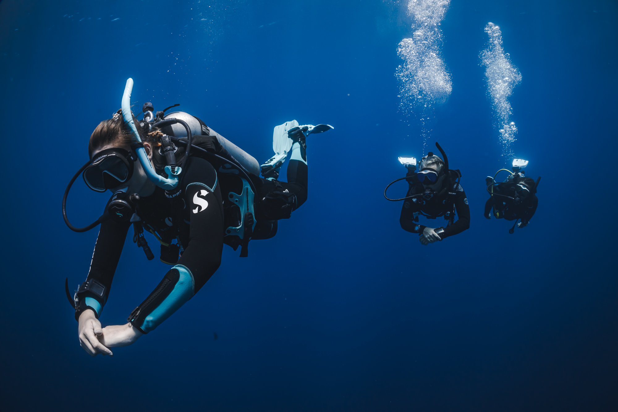three divers follow each other in the blue