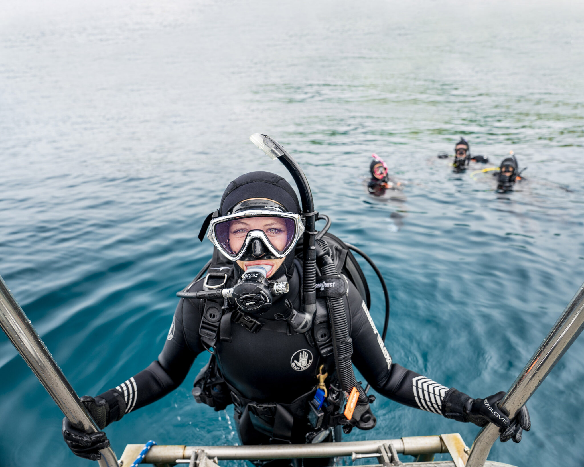 A woman climbs out of the water wearing scuba gear in new zealand