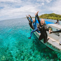 three divers jumping into water from a boat