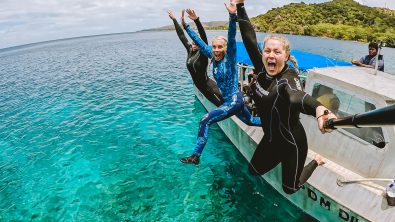 three divers jumping into water from a boat