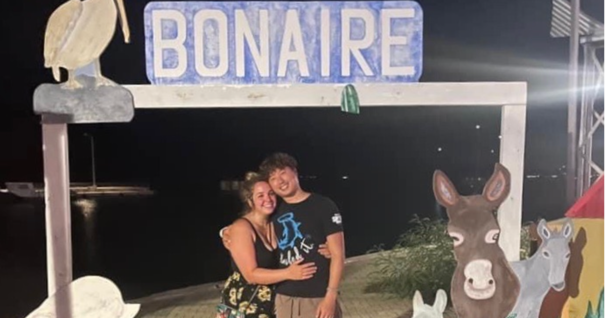 A couple poses under a Bonaire sign