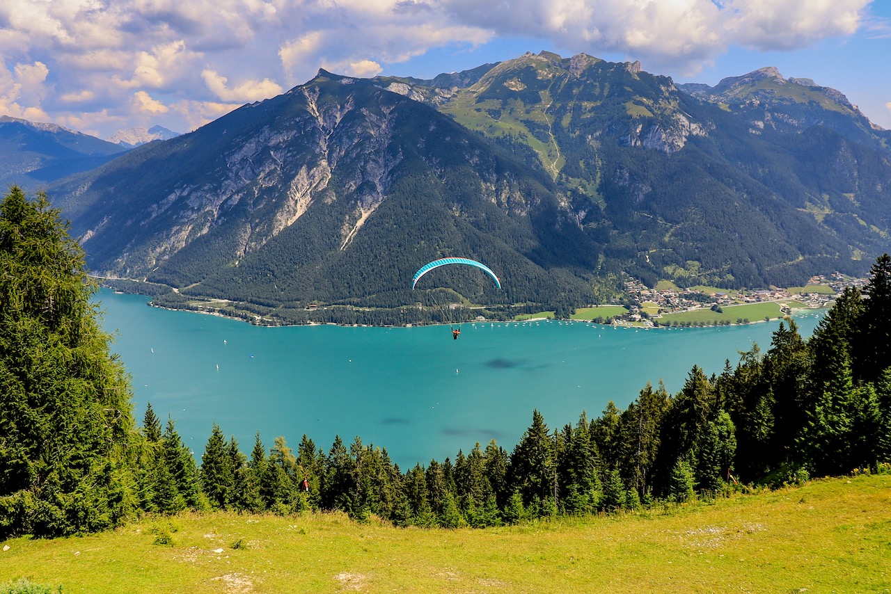 A paraglider over Achen lake, a picturesque alpine  lake with shimmering turquoise waters , offering swimming, sailing, boating and hiking. A view from cable car station above Pertisau.  Austria