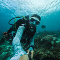 a scuba diver takes a selfie with a gopro camera