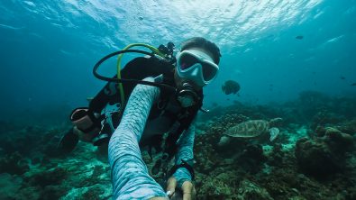 a scuba diver takes a selfie with a gopro camera