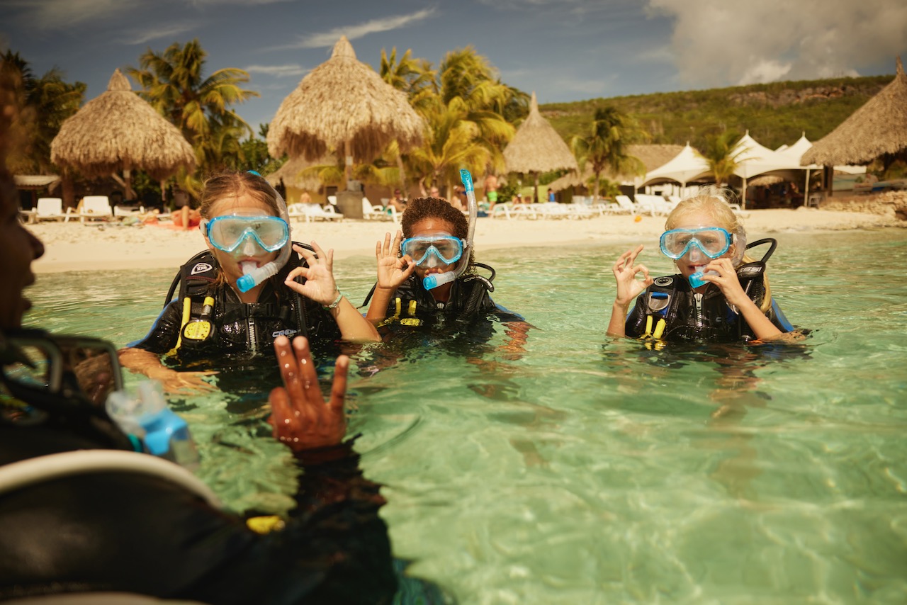 three children learn to dive in the shallows of a Caribbean island