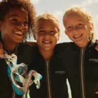 three young divers hug and smile for the camera