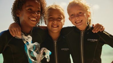 three young divers hug and smile for the camera