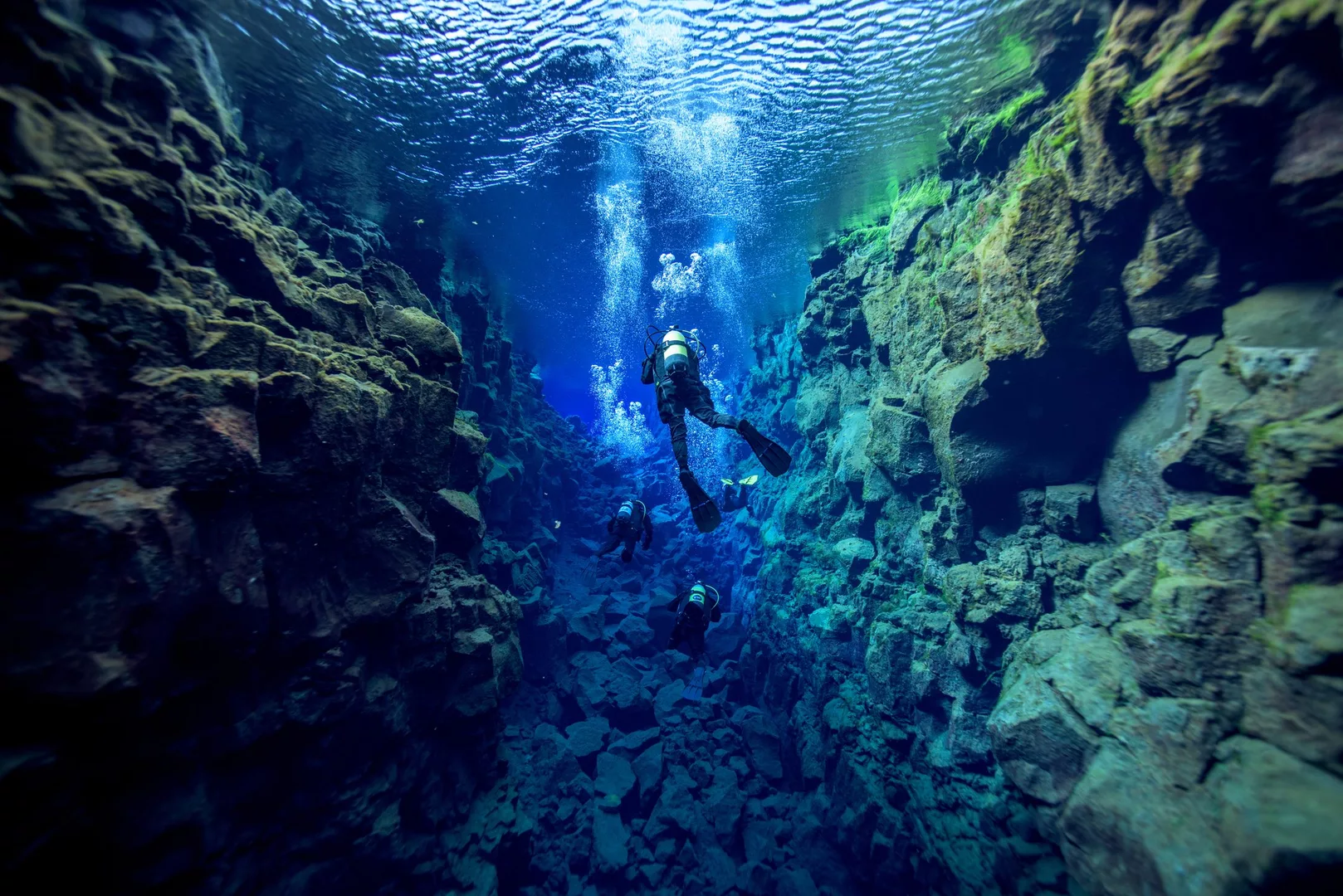 Divers swimming through Silfra canyon