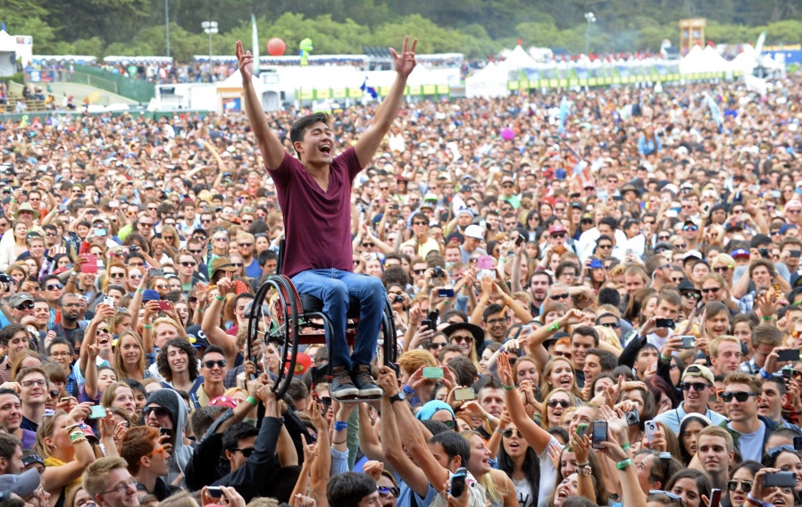 man in a wheelchair being held above a crowd