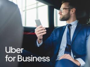 a business man wearing a suit and holding a phone sits in the back of an Uber