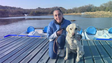 Jessica Pita with her dog Fudge smiling to the camera on a dock