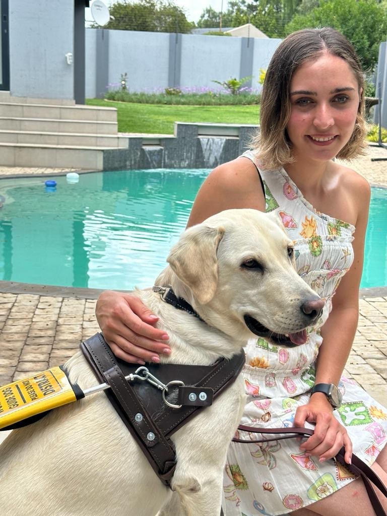 Jessica Pita smiling to the camera with her dog in front of a swimming pool