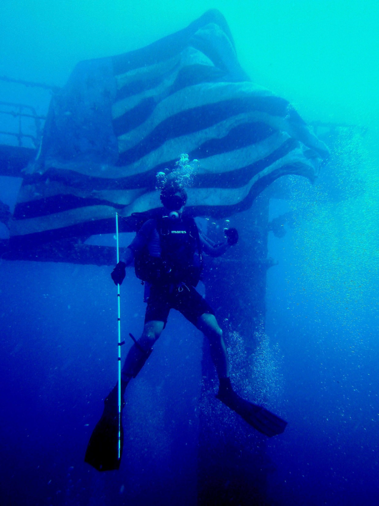 Michael Gray poses in front of the American Flag on a Key West shipwreck.