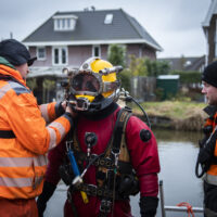 A commercial diver and explosives remover enters the water in a dive suit.