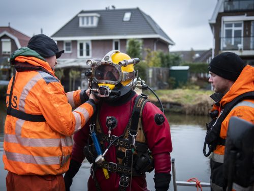 A commercial diver and explosives remover enters the water in a dive suit.
