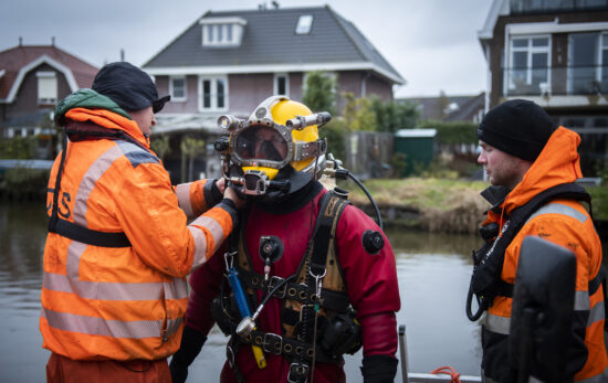 A commercial diver and explosives remover enters the water in a dive suit.