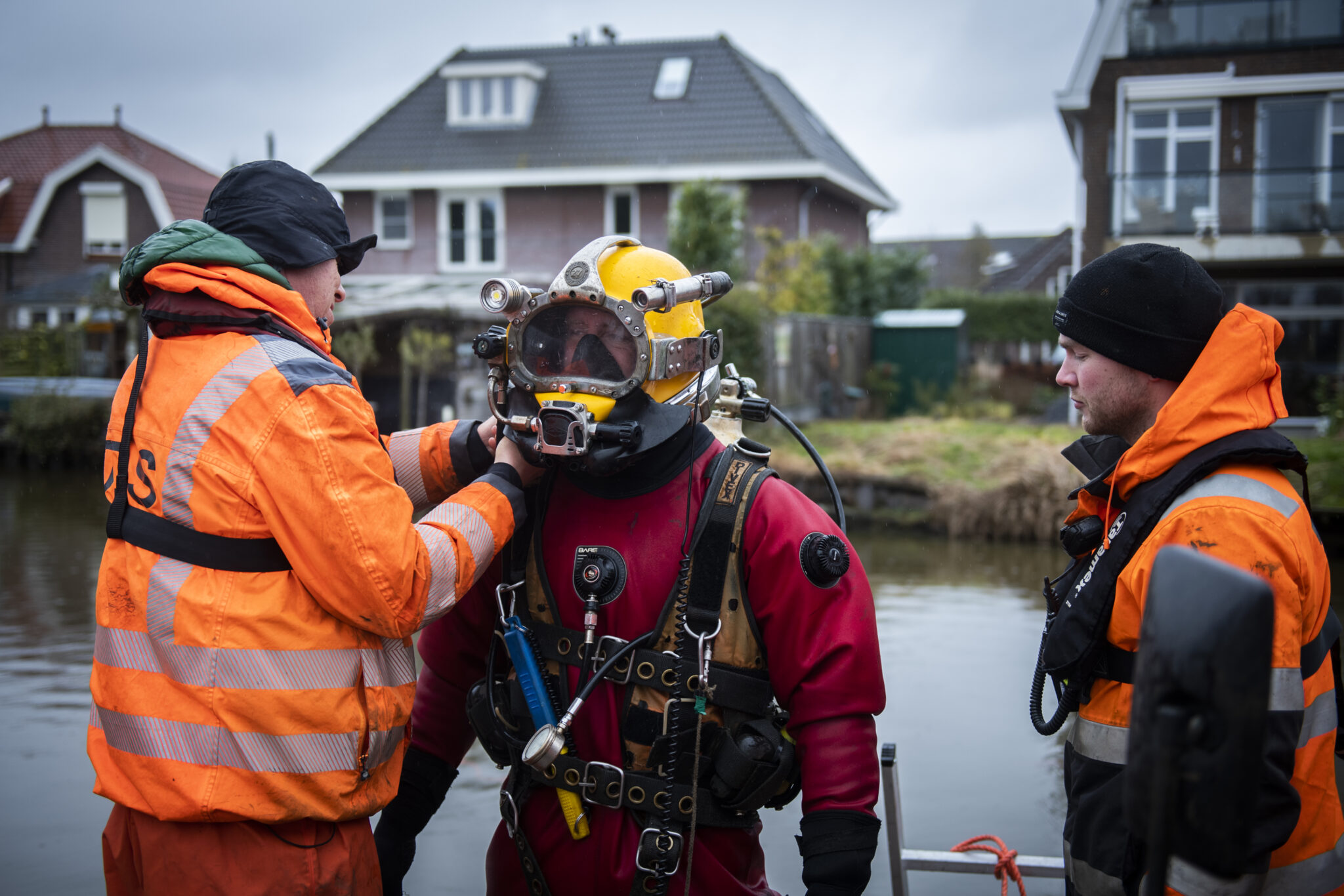 A commercial diver and explosives remover enters the water in a dive suit.