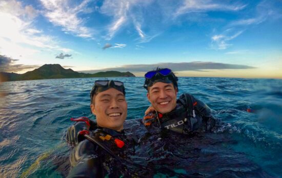 two divers taking a selfie at the surface