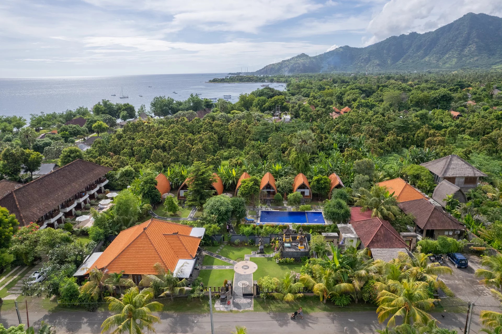 Aerial view of Kubu Padi resort with the ocean and mountains in the background