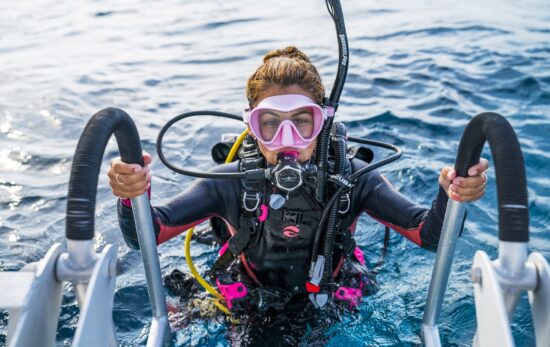 female diver just gets out of water and tries to get on the boat