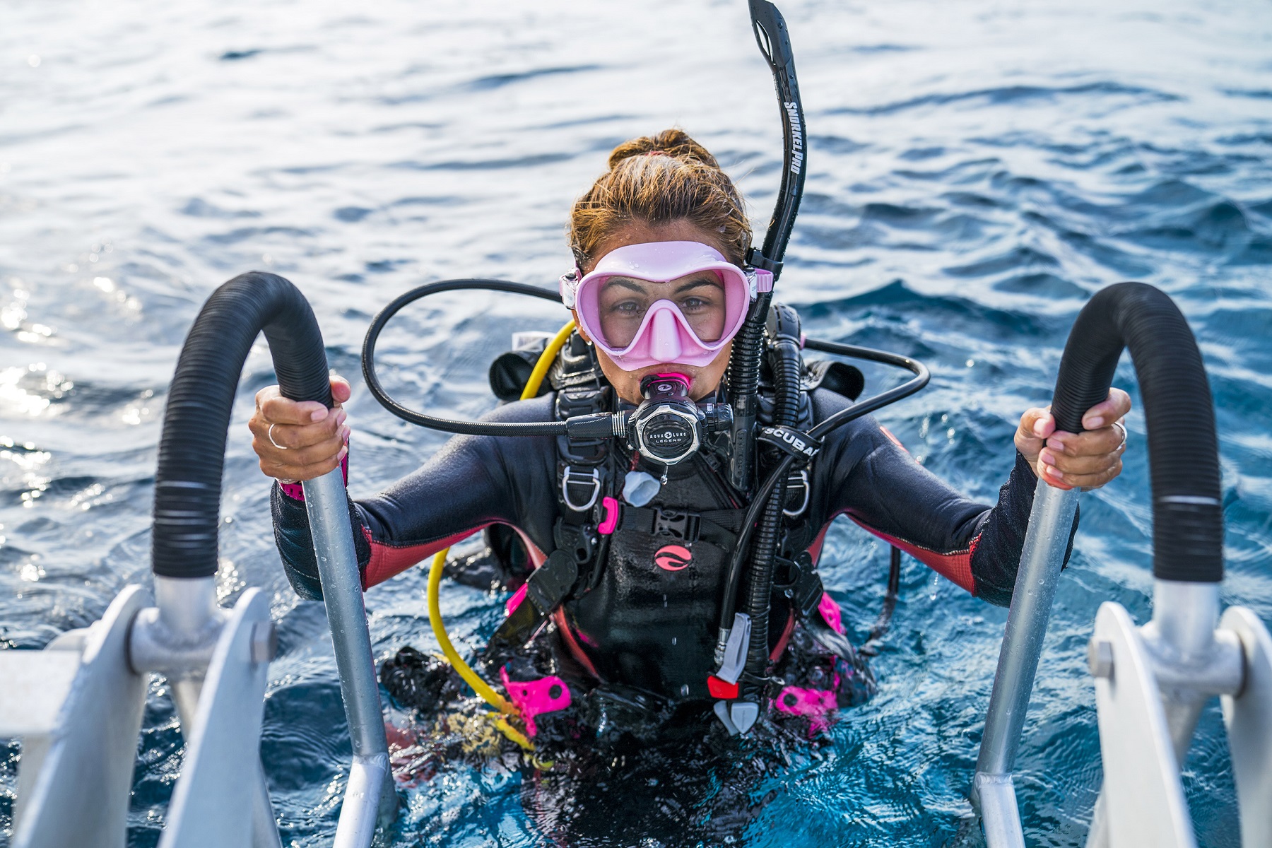 female diver just gets out of water and tries to get on the boat