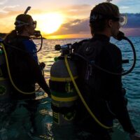 two divers entering in the water with their enriched air nitrox marked cylinders