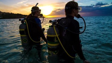 two divers entering in the water with their enriched air nitrox marked cylinders