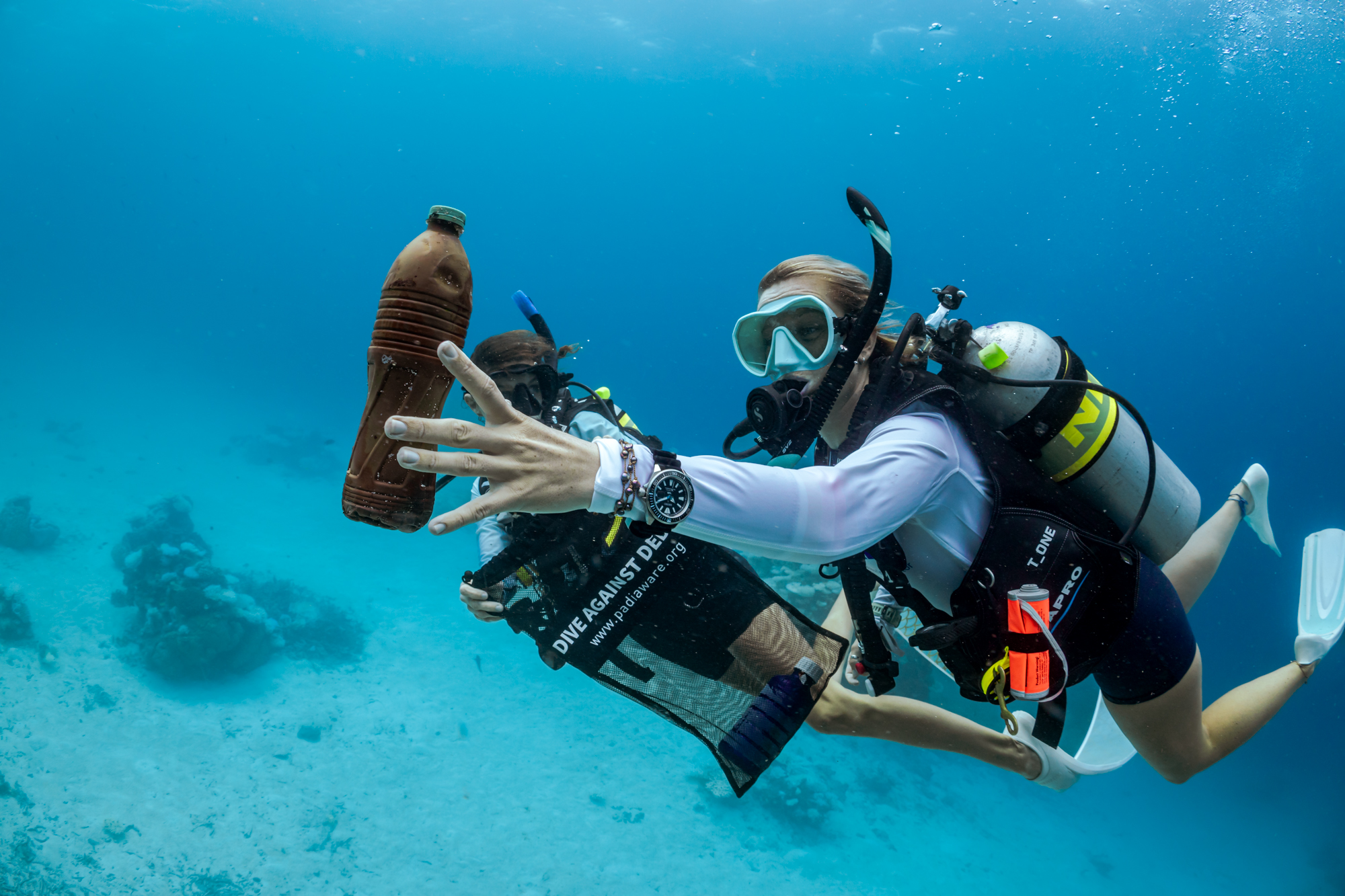 two divers in the maldives participate in a dive against debris to pick up plastic in the ocean. One diver is using nitrox.