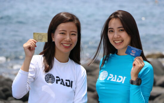 two ladies holding PADI standard c card on land