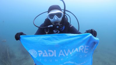 A diver holding a PADI AWARE flag in Iwa, Kangawa, Japan