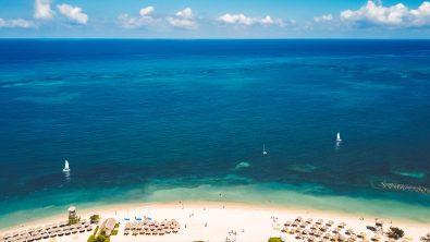 Clear, blue water and a sandy beach with umbrellas in Montego Bay Jamaica