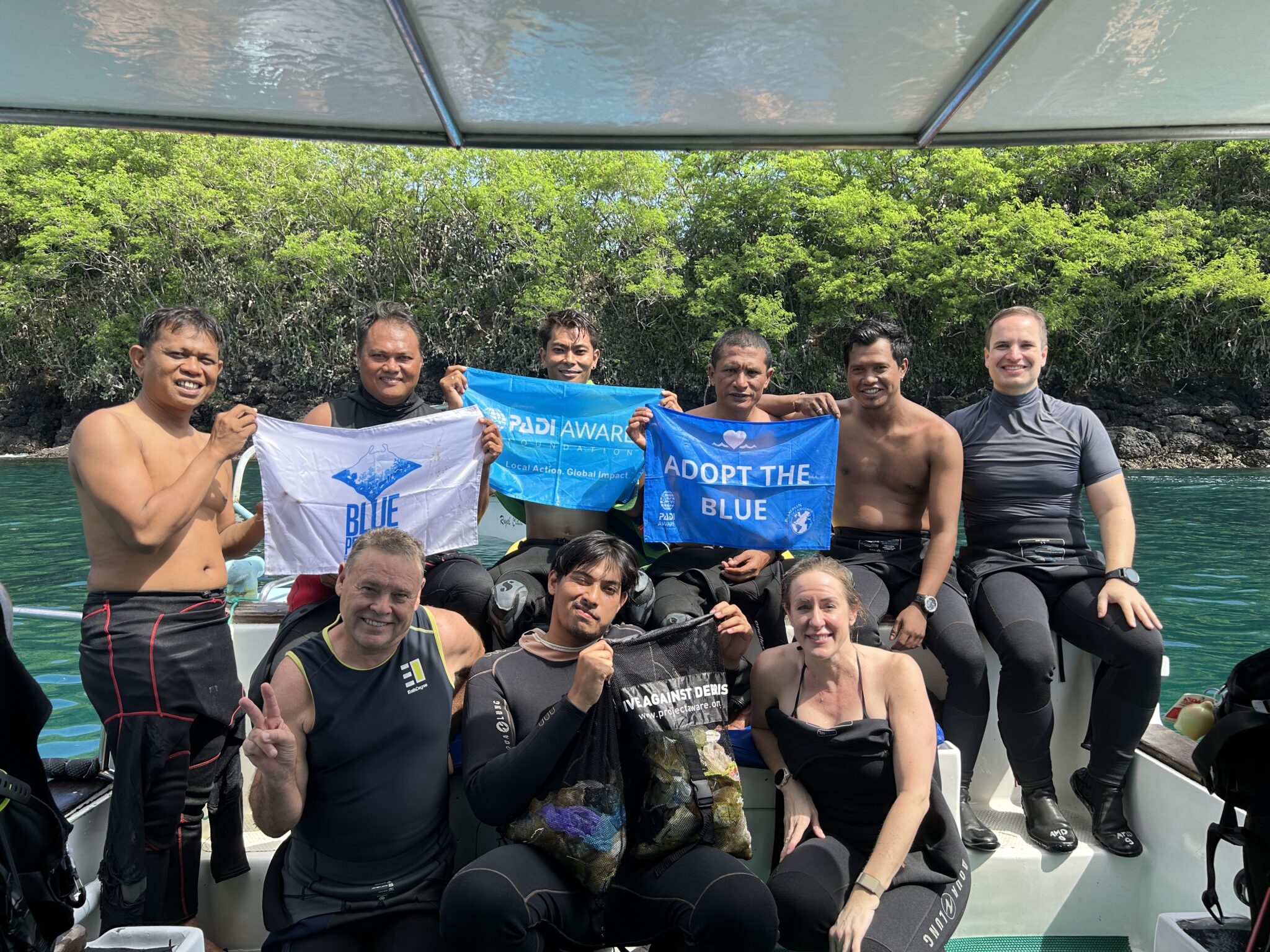 Scuba divers smiling for a picture and showing how they support conservation efforts.