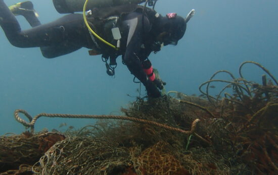 Scuba diver removing ghost fishing net.