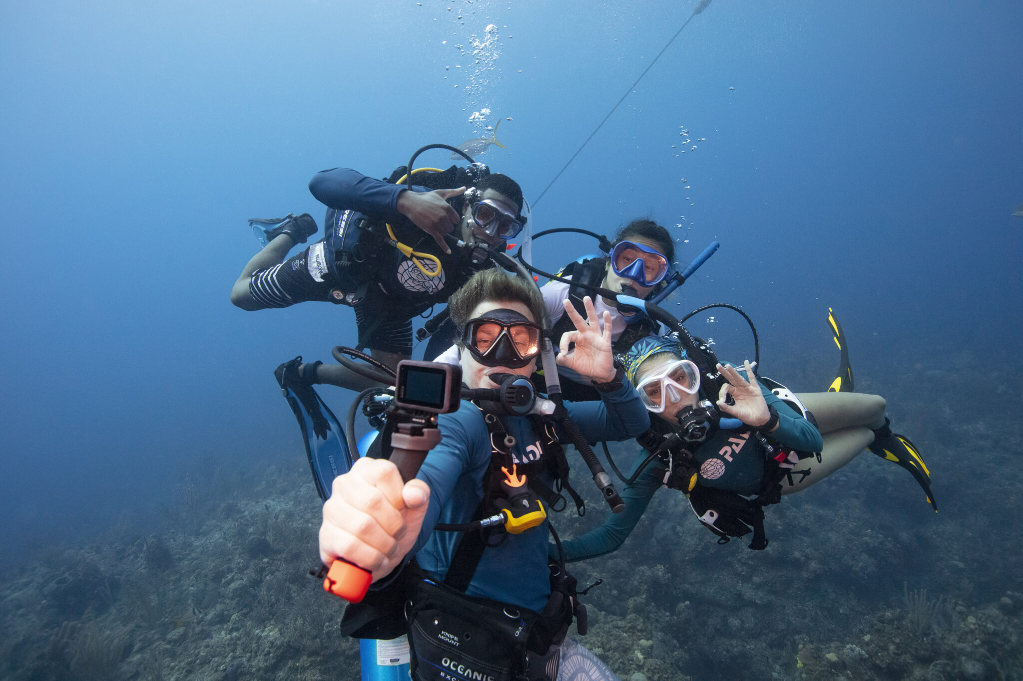 four divers taking underwater selfie with gopro