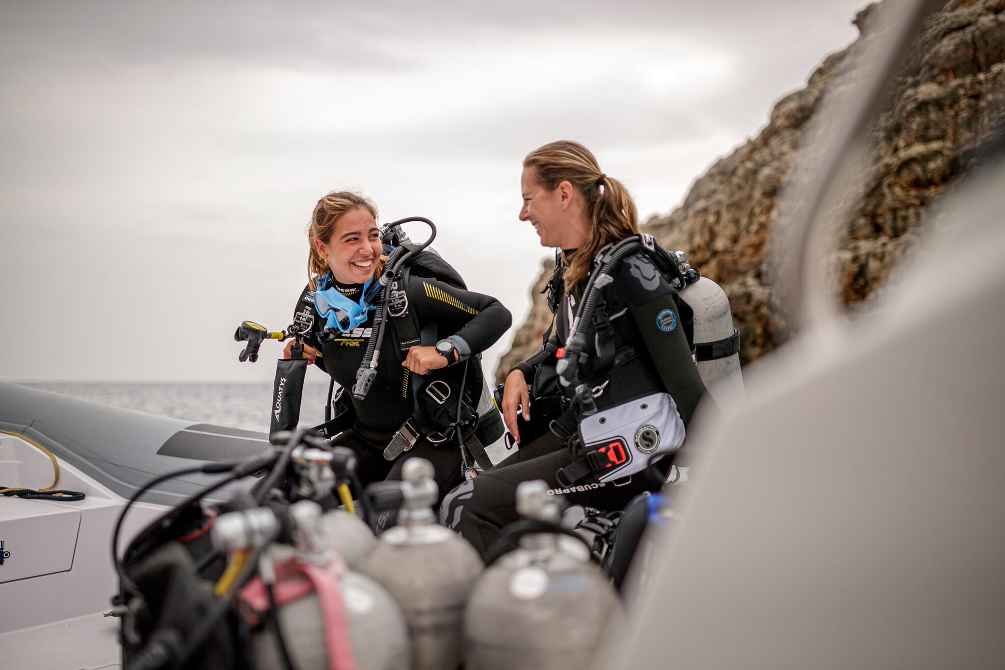 two divers laugh with each other as they get ready to go scuba diving from a boat