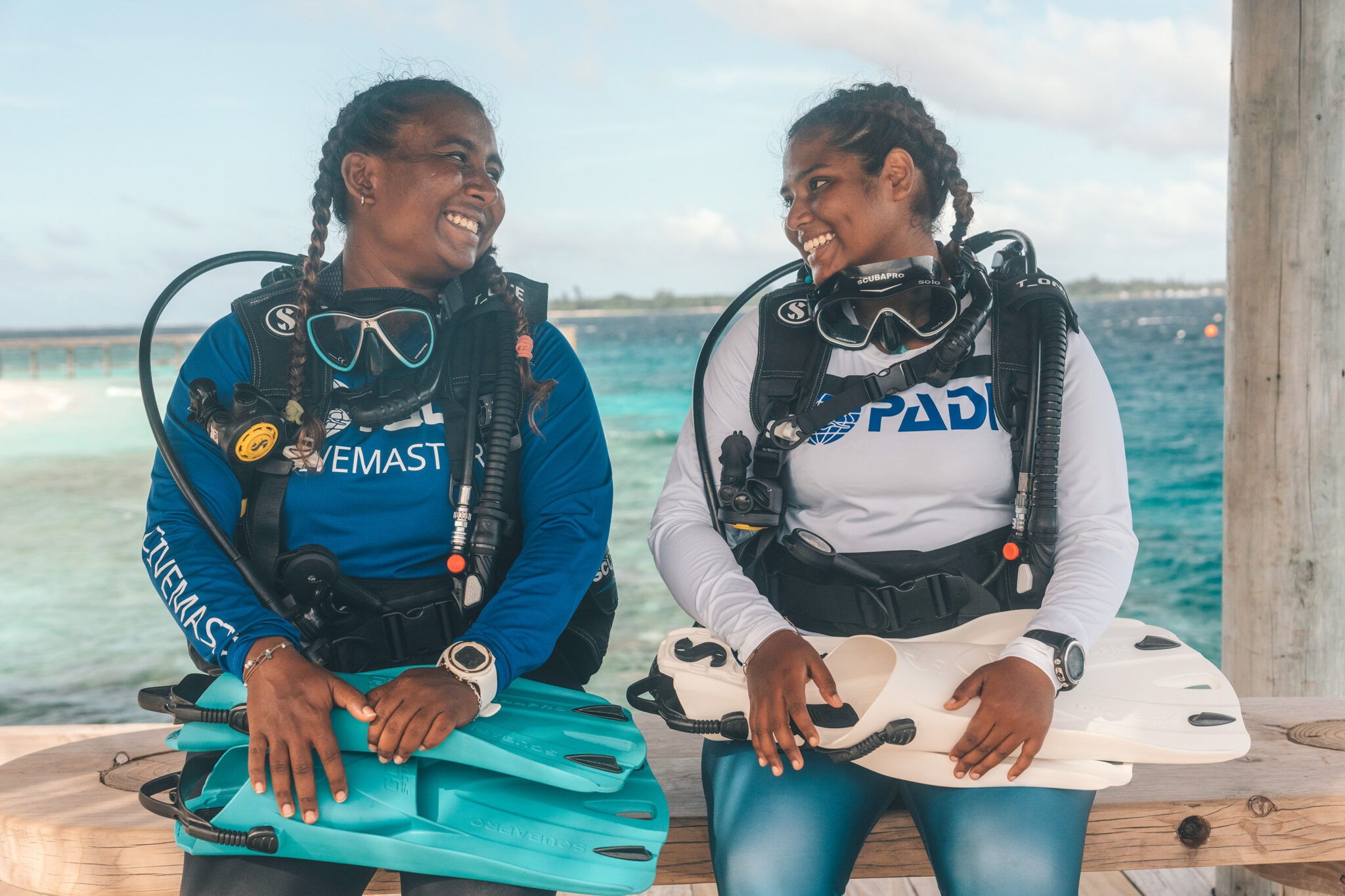 two divers smile at each other as they get ready to go scuba diving on a boat in the Maldives