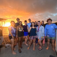 a group of people hang out on a boat in Hawaii at sunset