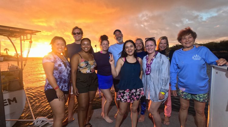 a group of people hang out on a boat in Hawaii at sunset