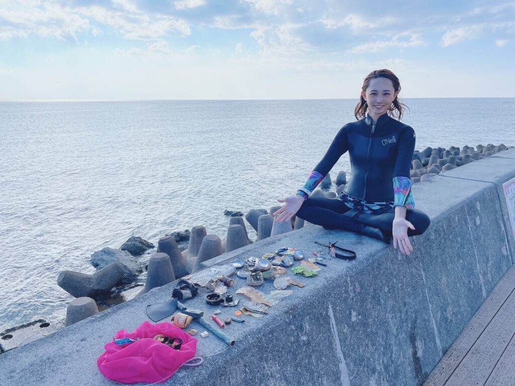 diver posing with trash collected from underwater, okinawa, japan