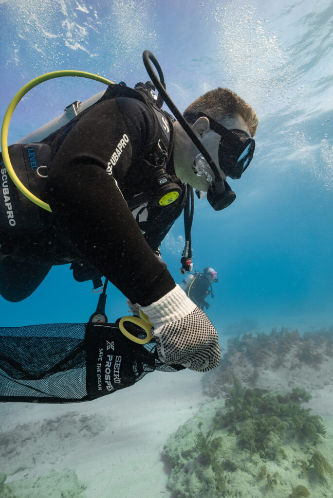 A scuba diver picks up garbage in a dive against debris bag