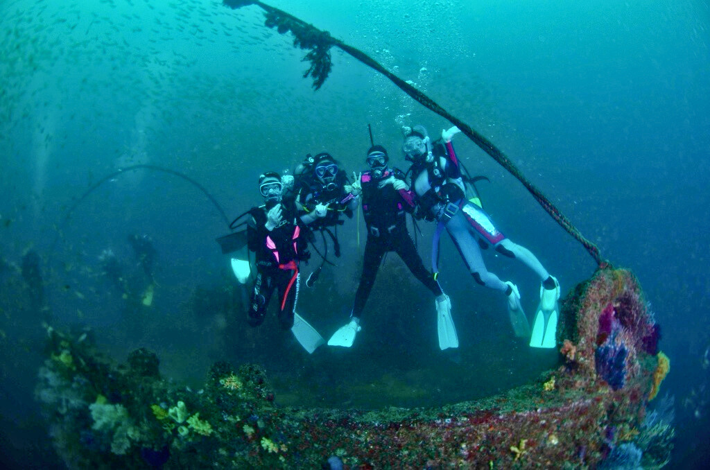 four divers posing infront of shipwreck