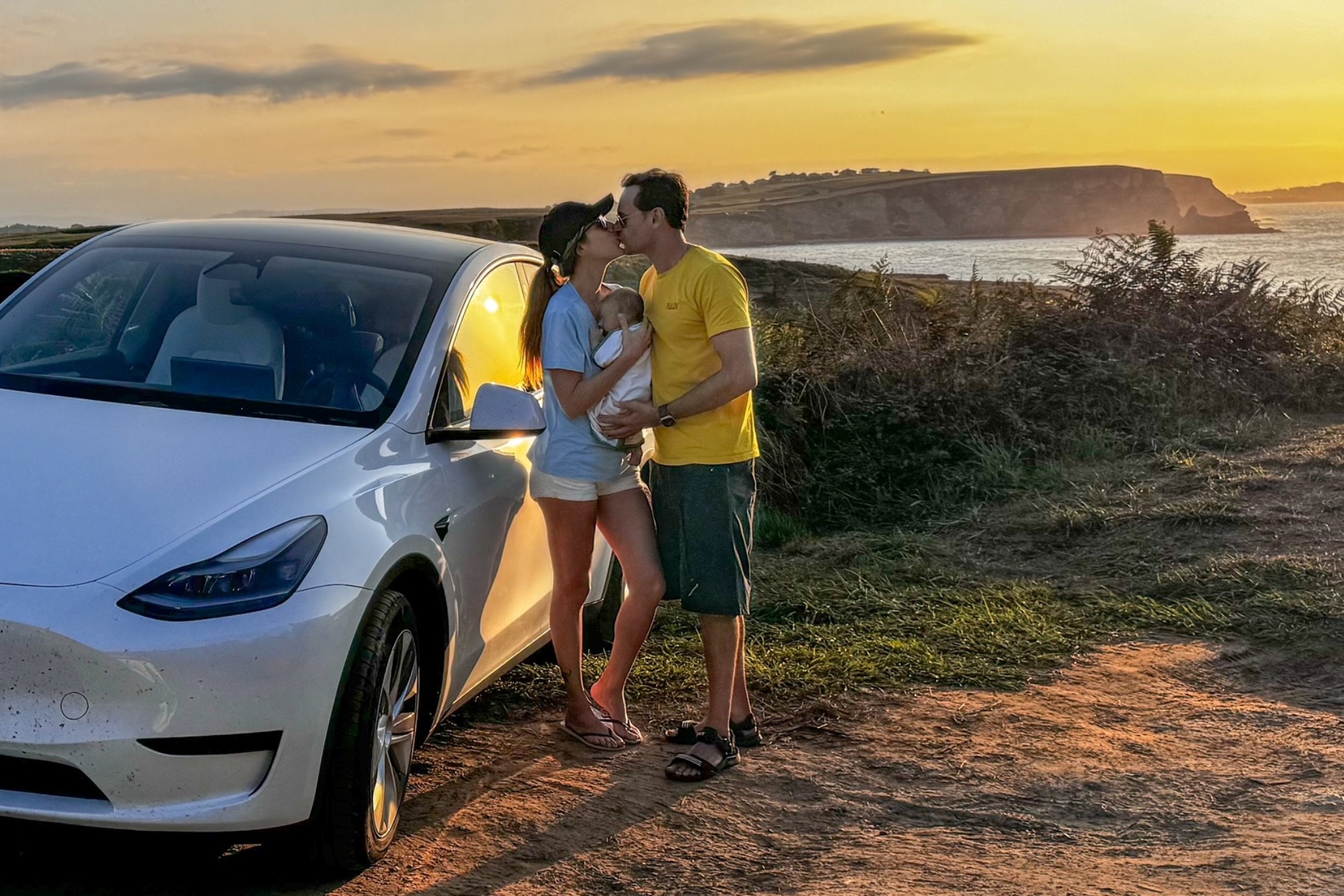 Family picture of Manuel, Alana and their baby next to their emission-free Tesla