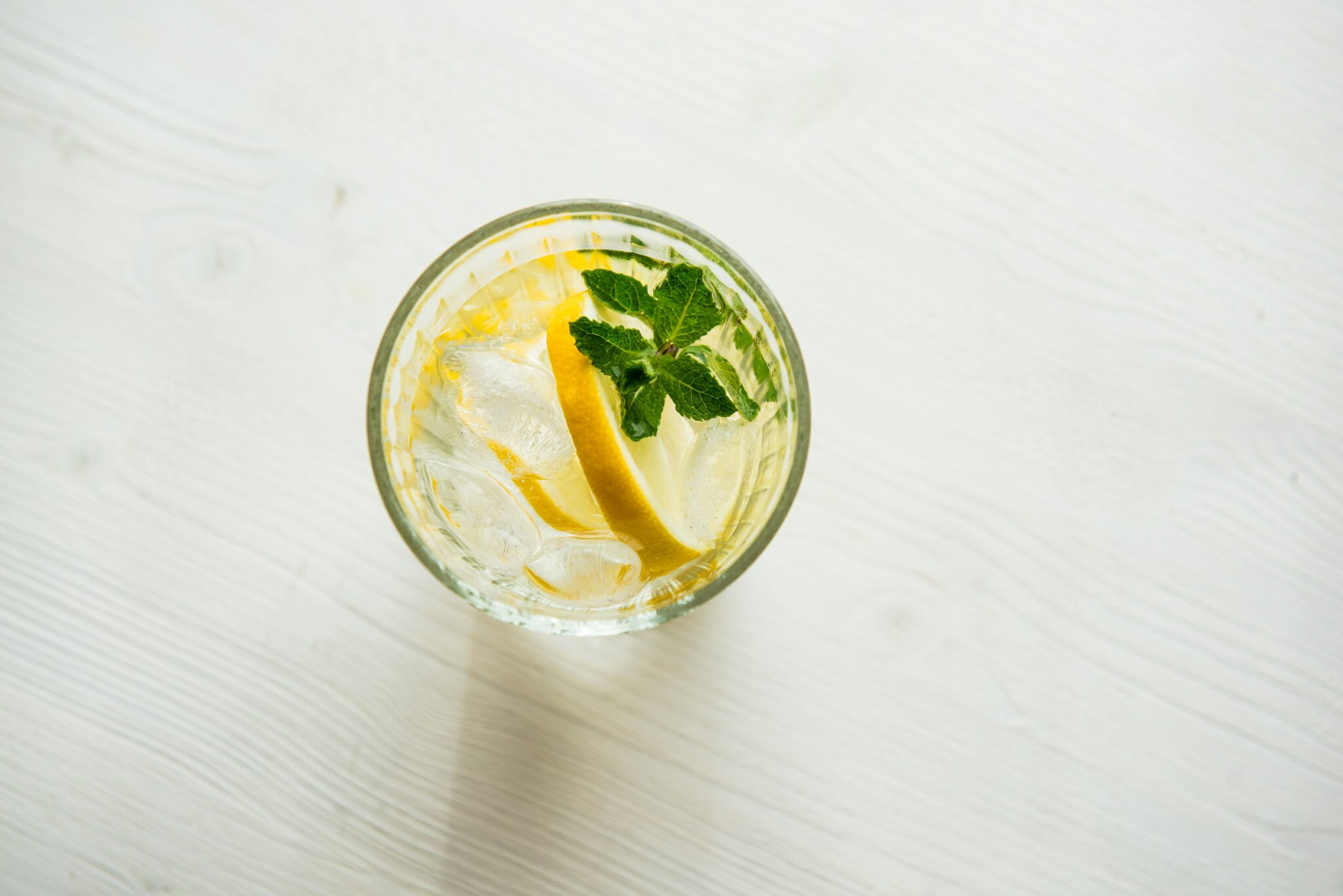 A photo taken from above of a clear glass filled with ice cubes and lemon, and which demonstrates that ice floats