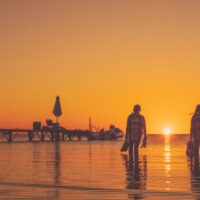 two divers enter the water together at sunset