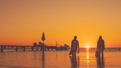 two divers enter the water together at sunset